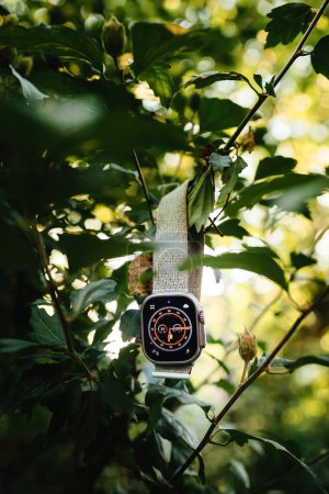 Foto de London, United Kingdom - Sept 28, 2022: New Apple Watch Ultra smartwatch hanged on a tree branch in garden - Imagen libre de derechos