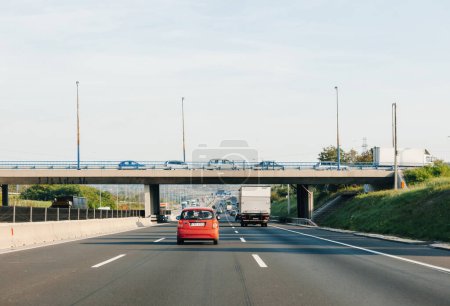 Téléchargez les photos : Hongrie - 30 sept. 2014 : Vue arrière d'une voiture rouge et d'un camion circulant sur l'autoroute Hungarys avec un pont plein de voitures au-dessus - en image libre de droit