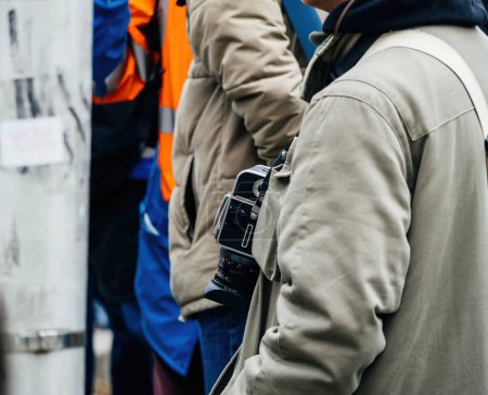 Téléchargez les photos : Strasbourg, France - 31 January 2023: Man wearing Hasselblad 503 cx 6x6 cm SLR waist-level finder around neck in city center - en image libre de droit