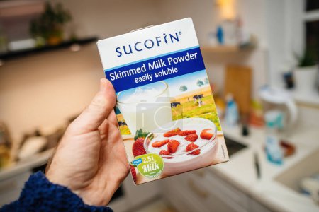 Téléchargez les photos : Allemagne - Jan 30, 2023 : POV main tenant paquet avec Sucofin lait écrémé en poudre facilement soluble - moderne fond de cuisine déconcentré - en image libre de droit