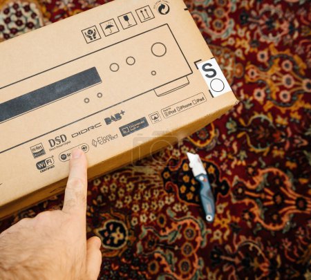 Foto de Paris, France - Dec 13, 2022: POV male hand pointing to Spotify DSD on the cardboard package of new Onkyo NS-6170 network audio player with DSD Hi-Res Audio and DSD DAB plus WIFI device during - Imagen libre de derechos
