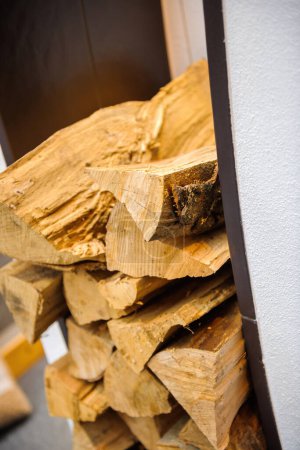 Téléchargez les photos : Stacked dried logs next to burning fire fireplace - enviromentaly friendly and economical heating - en image libre de droit