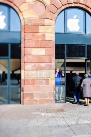 Foto de Estrasburgo, Francia - 20 de marzo de 2015: Trabajador de Apple Genius mirando al cielo admirando el eclipse solar total mientras los clientes entran en la tienda de computadoras - lente de cambio de inclinación - Imagen libre de derechos