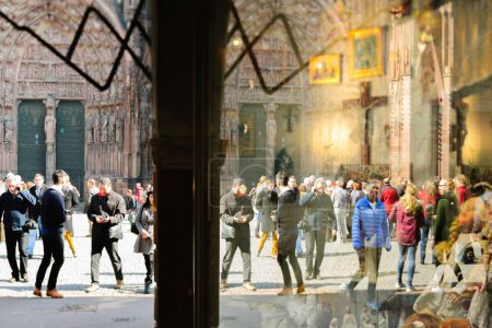 Téléchargez les photos : Strasbourg, France - 20 mars 2015 : foule de touristes piétons près de la cathédrale Notre Dame de Strasbourg Façade de l'entrée principale reflétée dans la vitrine de la boutique de souvenirs - en image libre de droit