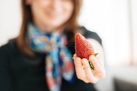 Photo for Woman hand offering enormous huge red strawberry Genetically modified organism - Royalty Free Image