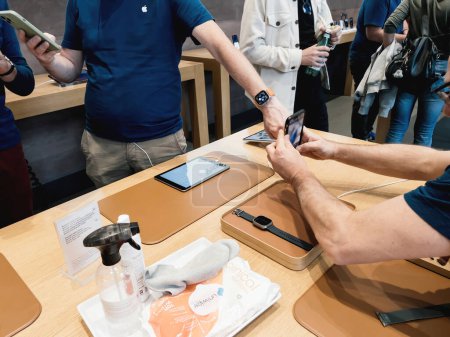 Foto de Paris, France - Sep 23, 2022: Genius Apple worker wearing new titanium Apple Watch Ultra during launch day - customers in background - Imagen libre de derechos