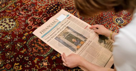 Foto de LONDRES, INGLATERRA - 20 DE OCTUBRE: Vista aérea de la mujer leyendo en el piso de la sala de estar la portada del Financial Times anunciando la renuncia de la Primera Ministra Liz Truss, en Westminster - Imagen libre de derechos