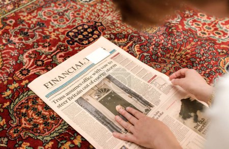 Foto de LONDRES, INGLATERRA - 20 DE OCTUBRE: Vista aérea de la mujer leyendo en el piso de la sala de estar la portada del Financial Times anunciando la renuncia de la Primera Ministra Liz Truss, en Westminster - Imagen libre de derechos
