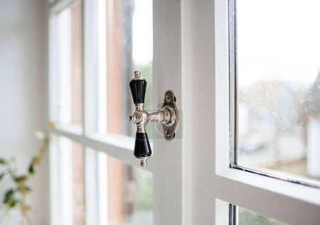 Foto de Classic window chrome stone handle on the wooden window - unfocused blur background - Imagen libre de derechos