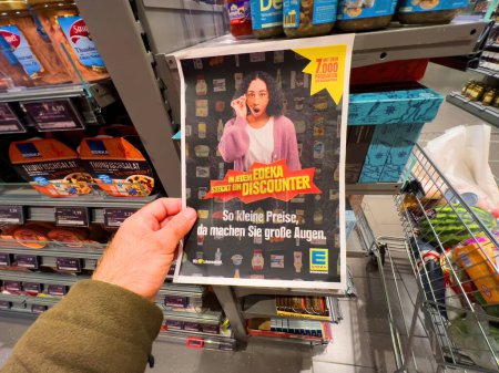 Foto de Alemania - Sep 24, 2022: POV papel de mano masculino con publicidad de precios bajos en el supermercado de descuento Edeka - Imagen libre de derechos