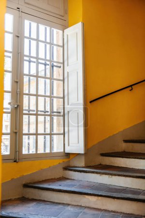Téléchargez les photos : Escalier majestueux dans le vieil Hausmannien un bâtiment avec une grande fenêtre couverte de soleil - en image libre de droit