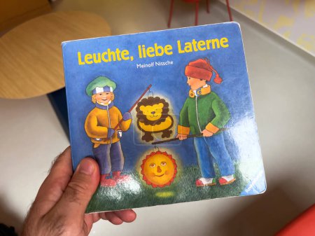Foto de París, Francia - 20 de octubre de 2022: POV mano masculina leyendo un libro de cuentos para niños Leuchte liebe Laterne de Meinolf Nitsche - Imagen libre de derechos