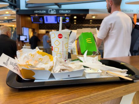 Foto de Frankfurt, Alemania - 17 / 08 / 2022: Bandeja con residuos de comida rápida dentro del restaurante McDonalds en el aeropuerto internacional de Frankfurt - antecedentes con el cliente en el punto de recogida - Imagen libre de derechos