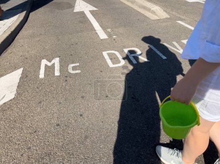 Téléchargez les photos : Londres, Royaume-Uni - 11 août 2022 : Une ombre de couple projetée sur la signalisation mCDrive sur le sol en asphalte dans le parking d'un fast-food McDonalds - en image libre de droit