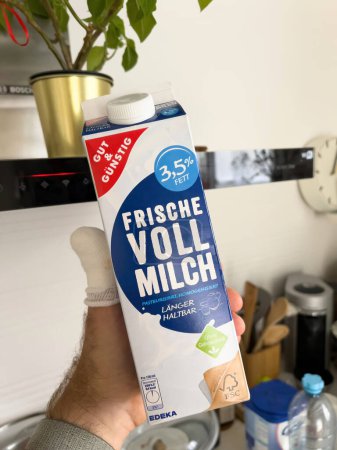 Photo for France - May 29, 2022: POV male hand holding Edeka Gut und Gunstig Fresh 3,5 whole milk - kitchen background - Royalty Free Image