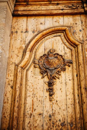 Téléchargez les photos : Détail de la vieille porte en Provence avec des fleurs et des décorations sculptées en bois de rose - immobilier de luxe vintage - en image libre de droit