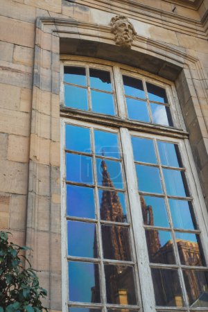 Foto de La fachada de piedra azul con de un edificio urbano se levanta alto en el sol del mediodía, su vista del ángulo bajo que destaca la arquitectura moderna impresionante catedral de Notre-Dame reflejada - Imagen libre de derechos