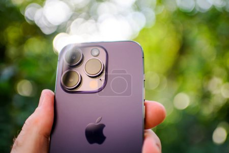 Téléchargez les photos : Londres, Royaume-Uni - 28 septembre 2022 : Gros plan d'une main tenant le nouvel iPhone 14 Pro, mettant en valeur sa technologie 5G et LTE dans un cadre de jardin - flou pour un effet esthétique agréable - en image libre de droit