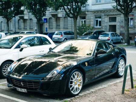 Téléchargez les photos : Paris, Fnance - 27 juin 2015 : Une élégante Ferrari noire garée dans une rue de la ville à l'extérieur d'une impressionnante structure architecturale. - en image libre de droit