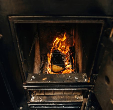 Téléchargez les photos : Image carrée de bois brûlant à l'intérieur kachelofen noir chauffant la maison pendant la hausse des prix du gaz - en image libre de droit