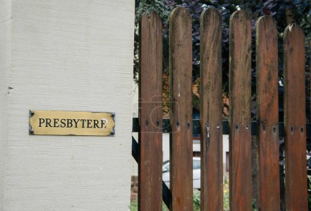 Téléchargez les photos : Une clôture en bois, ornée d'une affiche du presbytère en écriture occidentale, se tient silencieusement dans la journée communiquant la sécurité et l'avertissement à travers son texte. - en image libre de droit