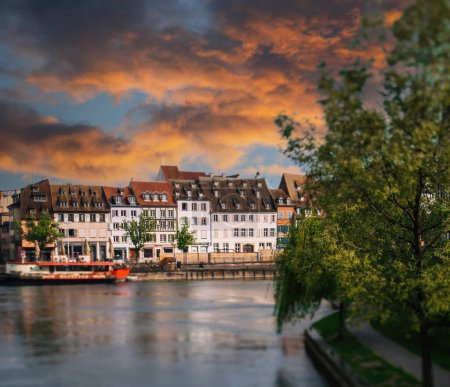 Téléchargez les photos : Strasbourg Paysage urbain rustique de la rivière au coucher du soleil avec une belle rivière malade et des bateaux - majestueuses maisons alsaciennes à colombages en arrière-plan - coucher du soleil rouge - en image libre de droit