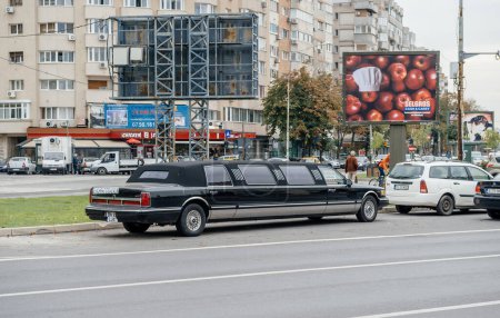 Photo for Bucharest, Romania - Oct 1, 2015: A black luxury vehicle, a limo, parked in front of an advertising board on the street of Bucharest Bucuresti to rent for events and transportation. - Royalty Free Image