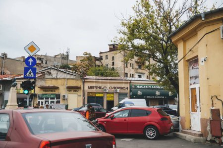 Téléchargez les photos : Bucarest, Roumanie - 1er octobre 2015 : Un quartier urbain animé, rempli de magasins et de personnes voyageant en voiture ou par tout autre moyen de transport - une vue sur un bâtiment laid à l'extérieur dans le mélange. - en image libre de droit