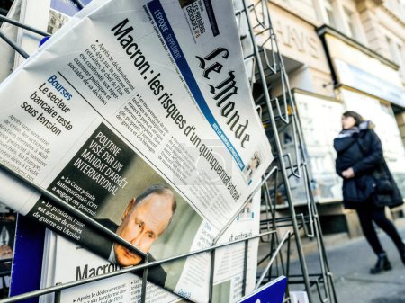 Foto de París, Francia - 20 de marzo de 2023: El presidente ruso es el blanco de una orden de detención internacional encabezada por una portada del periódico francés Le Monde con peatones de fondo - Imagen libre de derechos
