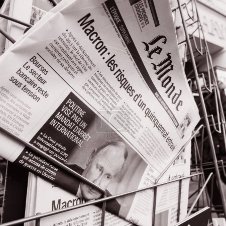 Foto de París, Francia - 20 de marzo de 2023: Imagen monocromática del presidente ruso atacado por una orden de detención internacional encabezada en una portada del periódico francés Le Monde con peatones de fondo - Imagen libre de derechos
