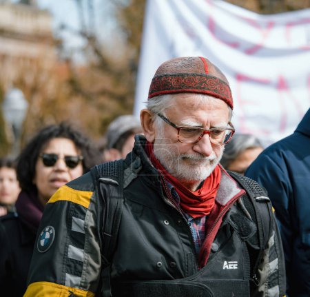 Téléchargez les photos : Strasbourg, France - 29 mars 2023 : Triste homme au chapeau tibétain asiatique manifestant à Strasbourg - La France connaît des semaines de protestations et de grèves liées à une hausse de l "âge de la retraite, qui était - en image libre de droit