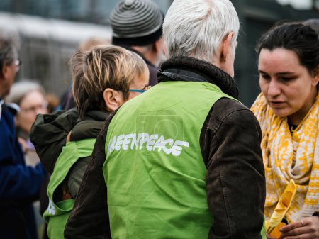 Foto de Estrasburgo, Francia - 29 de marzo de 2023: Vista trasera de un grupo de activistas adultos maduros y voluntarios con chaquetas Greenpeace se unen en protesta, sosteniendo carteles para el medio ambiente global - Imagen libre de derechos