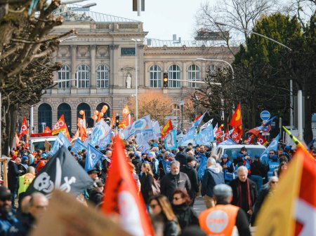 Foto de Strasborg, Francia - 29 de marzo de 2023: Se ve a una gran multitud de personas reunidas frente a un edificio exterior para protestar por el reciente aumento de la edad de jubilación - Imagen libre de derechos