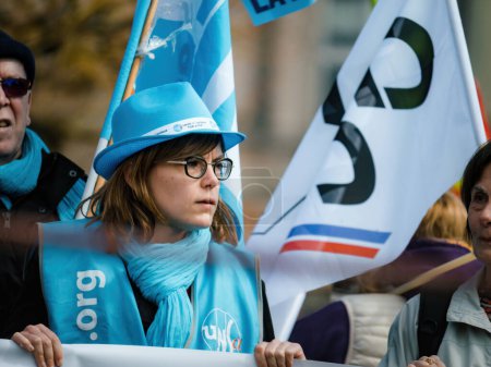 Foto de Strasborg, Francia - 29 de marzo de 2023: Un grupo de diversos adultos y jóvenes, liderados por una mujer con sombrero, protestan juntos por sus derechos de pensión - Imagen libre de derechos