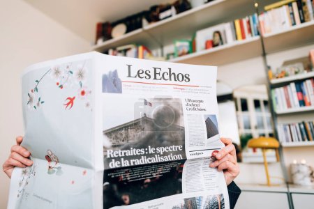 Foto de París, Francia - 20 de marzo de 2023: Vista frontal de una mujer leyendo el periódico francés Les Echos noticias de última hora de la adquisición histórica de UBS del rival Credit Suisse Group AG - el título UBS acepta comprar Credit Suisse - Imagen libre de derechos