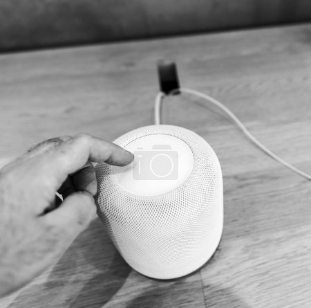 Foto de París, Francia - 20 de marzo de 2023: Nuevo y último Apple HomePod Assistant color blanco, incluido el sistema de reconocimiento activado Siri Voice Service, fotografiado en una mesa de madera., - Imagen libre de derechos