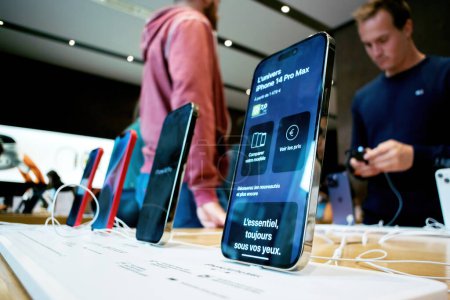 Photo for Paris, France - Sep 22, 2022: Charging Apple iPhone 14 Pro against a Apple Store background with screen on and name displayed - adults and childrens testing in background new devices - Royalty Free Image