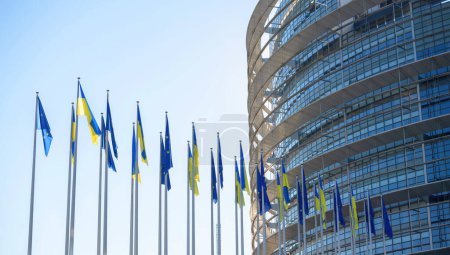 Téléchargez les photos : Le drapeau ukrainien flotte à côté du drapeau de l'Europe et tous les drapeaux syndicaux de l'UE devant les bureaux du bâtiment. La Russie poursuit son assaut sur les grandes villes du pays une semaine après le lancement d'un grand - en image libre de droit