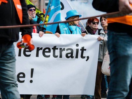 Foto de Strasborg, Francia - 29 de marzo de 2023: Un gran grupo de personas, hombres y mujeres por igual, están protestando en las calles de Estrasburgo con pancartas con texto para expresar su mensaje en contra del francés - Imagen libre de derechos