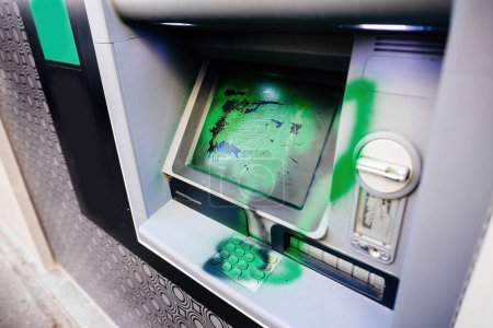 Photo for Graffiti-covered ATM in a European city, the aftermath of a protest demonstration with green paint - Royalty Free Image