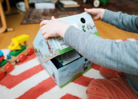 Téléchargez les photos : Francfort, Allemagne - Mar 12, 2023 : Un bébé mignon admirant la nouvelle boîte élégante de bottines Lowa Kids, entouré d'enfants fond de chambre - en image libre de droit