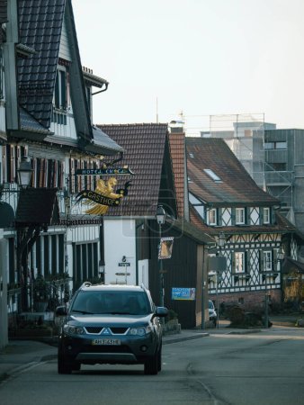 Foto de Achern, Alemania - 10 de febrero de 2023: Una tranquila zona residencial en Achern, región de Baden-Wurttemberg, Alemania, con edificios antiguos e infraestructura con una linda calle bordeada de casas, automóviles y una - Imagen libre de derechos