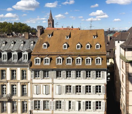 Foto de Un hermoso y tradicional edificio de estilo Haussmann en el corazón de París, con sus atractivas ventanas, terraza en la azotea y balcón adornado con plantas. Un encantador recordatorio del pasado de Europes. - Imagen libre de derechos