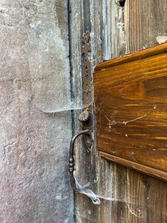 Téléchargez les photos : Un vieux mécanisme rouillé de serrure de porte recouvert de toiles d'araignées et de rayures de peinture pour une protection sûre d'une entrée extérieure. - en image libre de droit