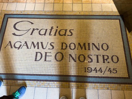 Photo for Vintage stone pavement with a beautiful mosaic, bearing the words Gratias Agamus Domino Deo Nostro, in an old basilica church - tourists feet in front of it - Royalty Free Image
