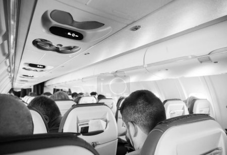 Téléchargez les photos : Vue intérieure d'une cabine d'avion remplie de passagers méconnaissables, prêts à partir en voyage dans le ciel. - en image libre de droit