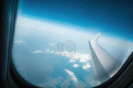 Téléchargez les photos : Un avion vole à travers le ciel bleu vif, ses ailes réfléchissant la lumière de la fenêtre vitrée à l'intérieur. Un moyen de transport parfait pour voyager et explorer - en image libre de droit