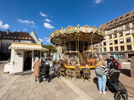 Foto de Estrasburgo, Francia - 21-sep-2022: Locales y turistas por igual se reúnen en la Place Gutenberg, Estrasburgo para disfrutar de la diversión del colorido carrusel en un contexto de impresionante arquitectura alsaciana. - Imagen libre de derechos