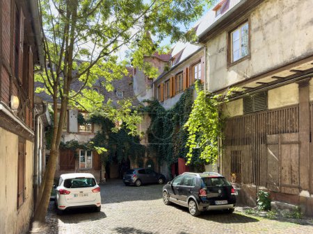 Photo for Strasbourg, France - Sep 21, 2022: An alley in a residential neighbourhood on a sunny summer day, featuring cars such as Ford and Volkswagen parked amongst trees and buildings. - Royalty Free Image