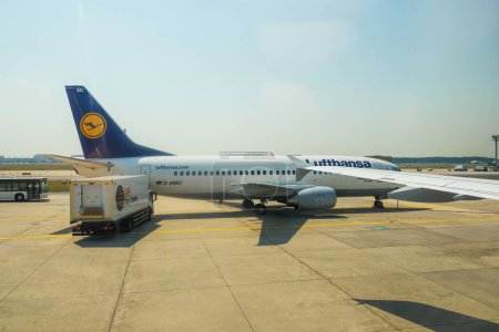 Téléchargez les photos : Allemagne - 6 juil. 2015 : Un Boeing Lufthansa 737-MSN 25149 arrive sur une piste d'aéroport, son ombre apparaît sur le tarmac comme un camion SkyChefs décharge et charge pour leur destination en Allemagne. - en image libre de droit